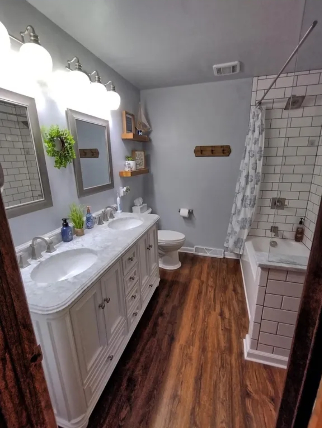 Bathroom after — double vanity, subway tile, wood accents
