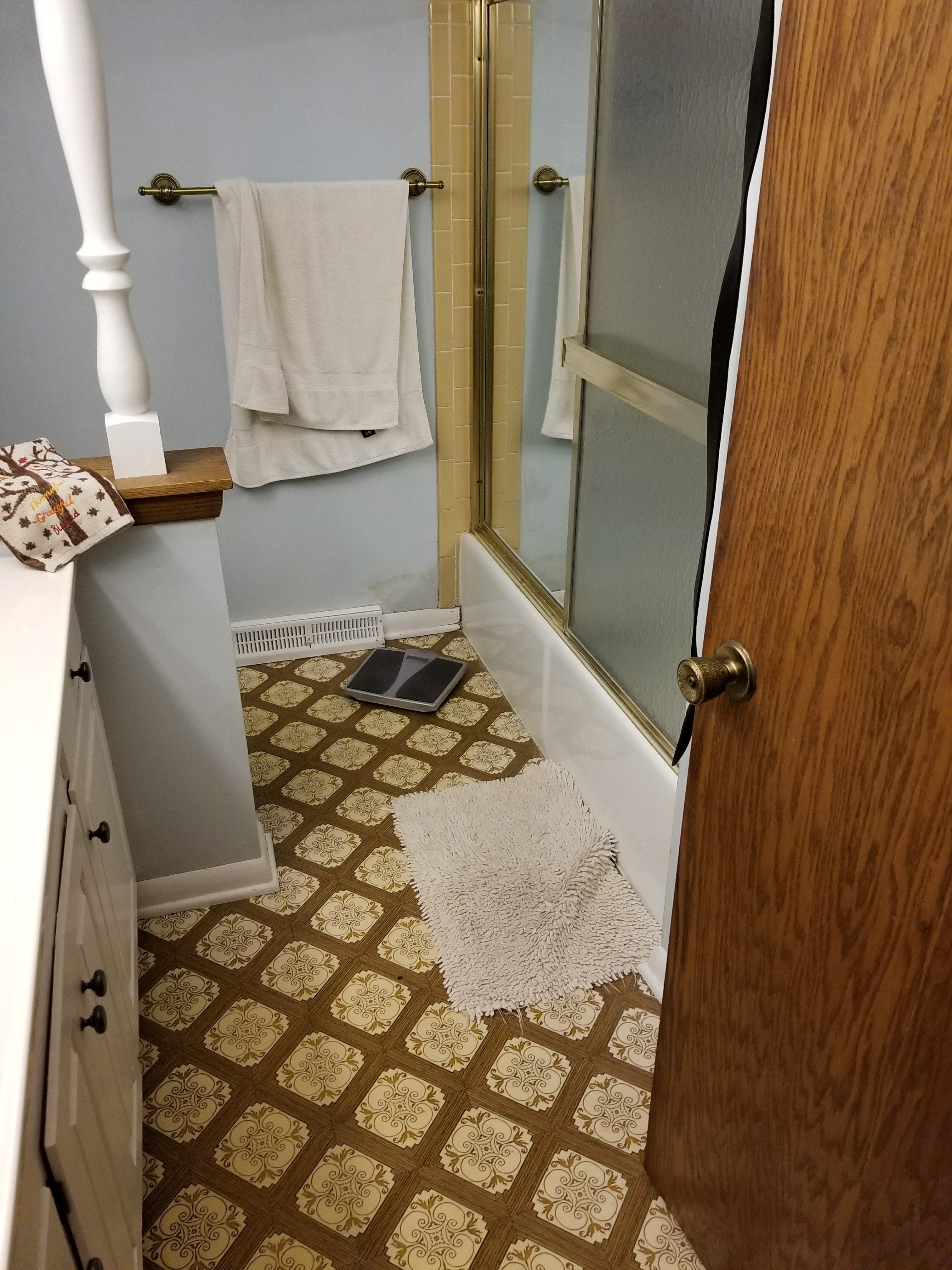 Bathroom before — vintage vinyl floor, outdated fixtures
