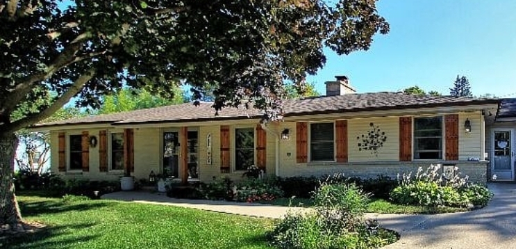 Exterior after — cedar board shutters, wood columns, styled entry