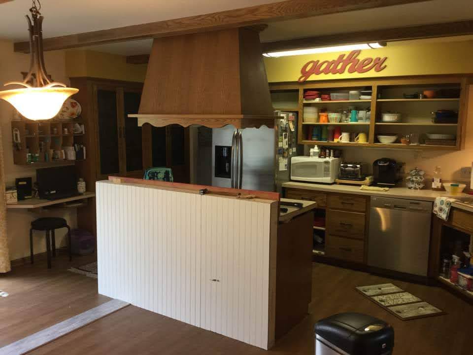 Kitchen before — dark oak cabinets, large hood, cluttered counters